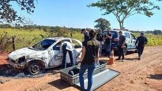 Políciais e equipe da perícia fazendo a remoção do cadáver de dentro do carro. (Foto: Viviane Oliveira)