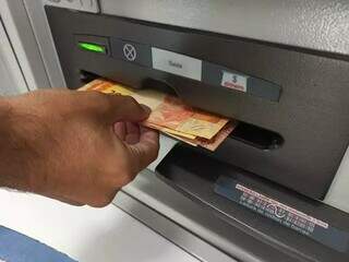 Cidadão sacando dinheiro em caixa eletrônico de agência bancária em Campo Grande (Foto: Kísie Ainoã/Arquivo)