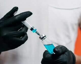 Profissional de saúde segurando seringa e ampola de vacina. (Foto: Cottonbro | Pexels)