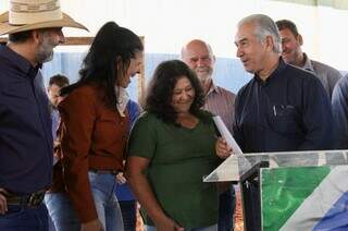 Moradora de Ivinhema, Maria José recebe título de rebularização fundiária das mãos do governador. (Foto: Divulgação)