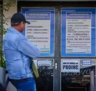 Trabalhador na porta da Funsat olha para cartaz que mostra fim de vagas no Proinc. (Foto: Arquivo)