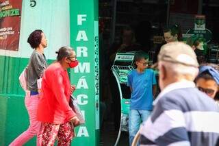 Idosos passando por farmácia, na Rua 14 de Julho, no centro de Campo Grande (Foto: Henrique Kawaminami)