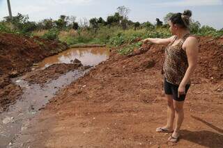 Moradora da Rua Indianápolis, dona de casa Suelen Lopes Corrêa, de 33 anos, mostra esgoto represado em buraco aberto com escavadeira (Foto: Kísie Ainoã)