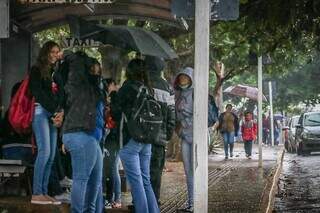 Estudantes usam guarda-chuva e se protegem em ponto de ônibus. (Foto: Henrique Kawaminami)