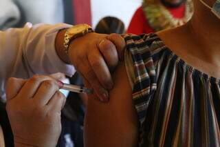 Mulher é recebe dose de vacina contra a covid-19 em Campo Grande. (Foto: Kísie Ainoã)