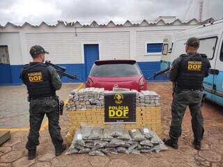 Policiais diante da droga apreendida com o traficante. (Foto: DOF) 