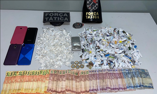 Dinheiro, celulares e papelotes de drogas apreendidos com os criminosos. (Foto: Polícia Militar) 
