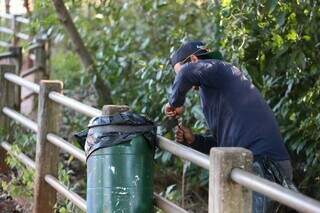 Funcionário prende saco de lixo com borracha para plástico não ser furtado. (Foto: Marcos Maluf)