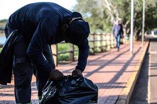 Funcionário da Sisep recolhe saco de lixo no entorno do Lago do Amor. (Foto: Marcos Maluf)