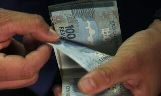 Notas de R$ 100 são contadas após saque (Foto: Agência Brasil)