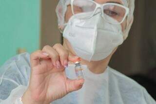 Ampola de vacina conctra a covid na mão de profissional de saúde, em Campo Grande. (Foto: Marcos Maluf/Arquivo)