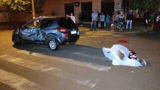 Corpo da vítima coberto por lençol branco atrás do veículo envolvido na batida. (Foto: Adilson Domingos)
