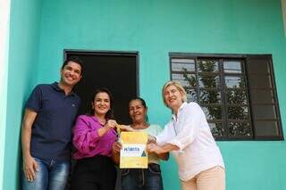 Ao lado de diretores das agências e da prefeita Adriane Lopes, dona Ambrósia recebe chave de casa. (Foto: Henrique Kawaminami)