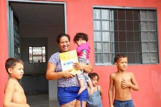 Na porta de casa, a diarista exibe sorriso ao lado de quatro dos seis filhos. (Foto: Henrique Kawaminami)