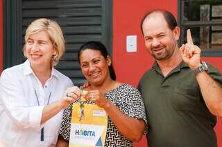 Érica e Genival recebem chave da diretora presidente da Agehab, Maria do Carmo. (Foto: Henrique Kawaminami)