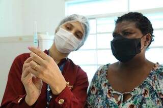 Enfermeira mostra dose de vacina contra a covid para paciente. (Foto: Kísie Ainoã/Arquivo)