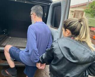 Psicólogo é colocado na viatura por delegada, após ser preso em casa (Foto: Divulgação)