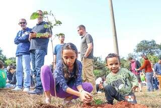 Crianças plantando árvores de ipês durante uma ação na Capital. (Foto: Henrique Kawaminami)