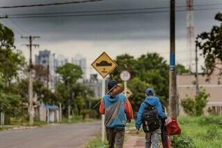 Paulo Américo com a enxada nas costas acompanhado pelo filho de 12 anos (Foto: Marcos Maluf)