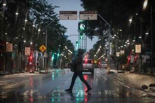 Mulher atravessa 14 de Julho protegida da chuva (Foto: Henrique Kawaminami)