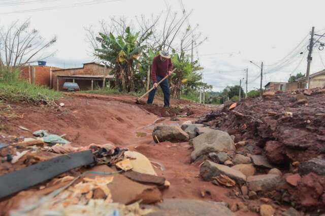 Em rua sem asfalto, morador cobre com terra vala aberta pela chuva
