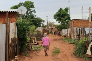 Senhora caminha entre as casas da Comunidade do Angico, em Campo Grande. (Foto: Paulo Francis)