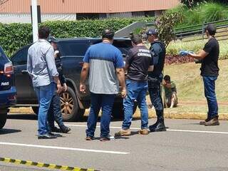 Sentado no chão, de verde, irmão da vítima chora e fala ao telefone (Foto: Ana Oshiro)