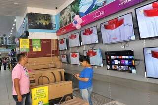Vendedor mostrando TVs para cliente em loja do centro da cidade (Foto: Paulo Francis)