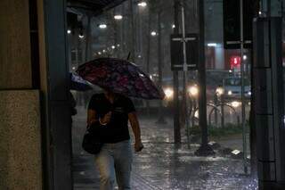 Pedestre se protegendo da chuva no centro da Capital (Foto: Henrique Kawaminami/Arquivo)