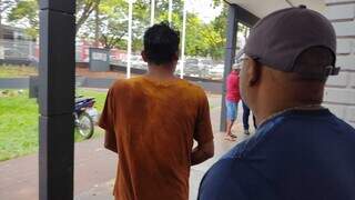 Homem, de camiseta de cor laranja, que estuprou a tia chegando à delegacia (Foto: Adilson Domingos) 