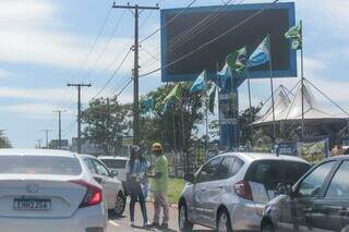 Cabos eleitorais oferecem adesivos em frente a comitê de campanha na Avenida Afonso Pena. (Foto: Marcos Maluf)