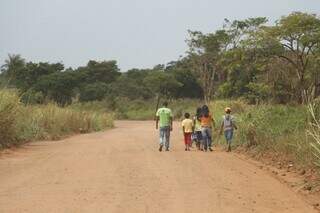 Familia segue a pé por estrada da Aldeia Tey Kuê, onde crime aconteceu (Foto: Helio de Freitas)