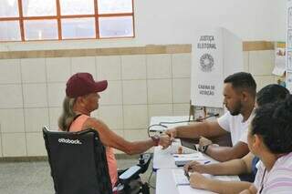 Mesário colhendo digital de eleitor em seção de Campo Grande (Foto: Paulo Francis)
