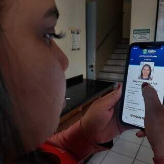 Eleitora acessa aplicativo e-título em smartphone. (Foto: Caroline Maldonado)