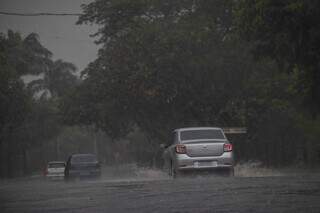 Veículos trafegam em via com chuva no Piratininga, em Campo Grande. (Foto: Marcos Maluf)