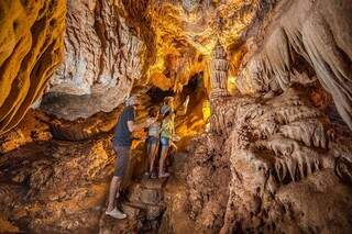 No interior da gruta turistas contemplam uma das formações esculpidas pela natureza que lembram a torre de igreja - Foto: Reprodução