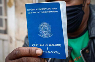 Homem exibe carteira de trabalho na fila da Funtrab, em Campo Grande. (Foto: Henrique Kawaminami)