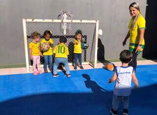 Crianças durante formação de time em campo, com atividade de tema da Copa. (Foto: Escola Criatividade)