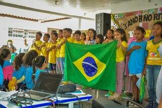 Alunos cantando o Hino Nacional durante apresentação com tema de Copa do Mundo. (Foto: Semed)