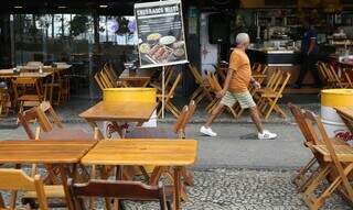 Homem caminha em frente a restaurante. (Foto: Agência Brasil)