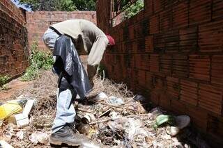 Profissional da prefeitura durante limpeza de terreno baldio com itens que podem acumular água. (Foto: Kísie Ainoã)