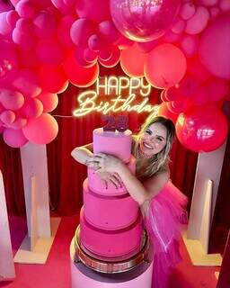 Empresária abraçada com o bolo e rodeada de balões rosas. (Foto: Arquivo pessoal)