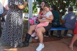 Ana Paula sentada no ponto de ônibus, com a filha no colo (Foto: Marcos Maluf)