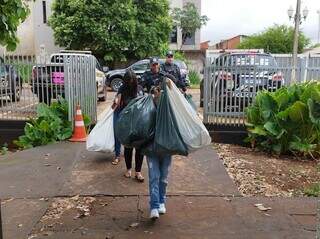 Presos por série de crimes chegam à delegacia carregando sacos com produtos furtados (Foto: Adilson Domingos)