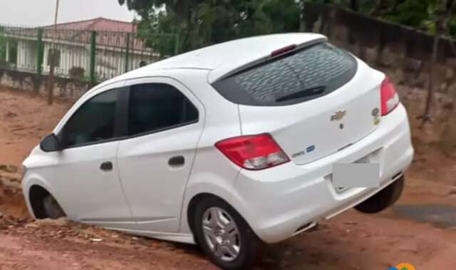 Carro fica &quot;pendurado&quot; em valeta aberta durante temporal