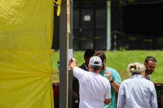 Notificação sendo colada por policial civil em uma das tendas. (Foto: Henrique Kawaminami)