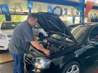 Luiz Carlos confere mecanânismos de um carro seminovo na garagem da loja (Foto: Natália Olliver)