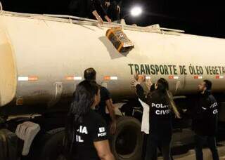 Policiais retirando os trabletes de droga do caminhão utilizado em transporte de óleo vegetal (Foto: divulgação/PCDF)
