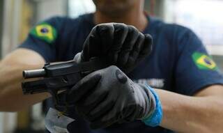 Policial remove munição de pistola. (Foto: Marcello Casal Jr/Agência Brasil)