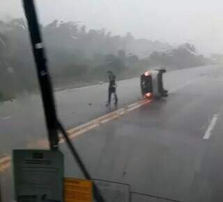 Condutor perde controle em rodovia molhada, carro capota e para no meio da pista